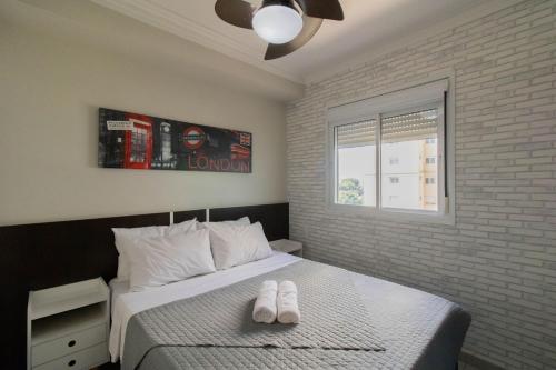 1 dormitorio con 1 cama con 2 zapatillas blancas en Apartamento 408 em condomínio de alto padrão en Guarulhos