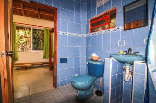 a blue bathroom with a blue toilet and a sink at Playa Lakin-ha beachfront cabins in Tulum