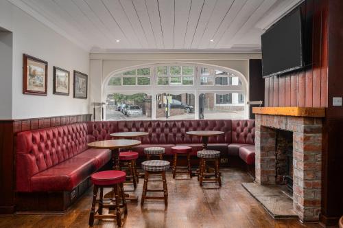 a bar with a red leather couch and tables and a fireplace at Elephant and Castle in Wakefield