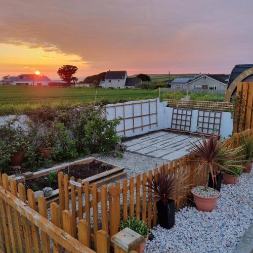 a backyard with a wooden fence and some plants at Hegarty's cottage at Trevarrian Lodge in Mawgan Porth