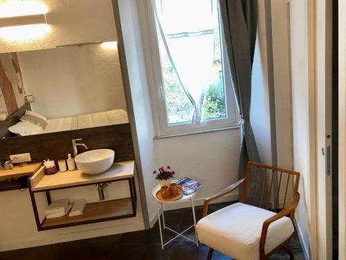 a bathroom with a sink and a mirror and a chair at DIMOR'A' ROOMS in Pitigliano