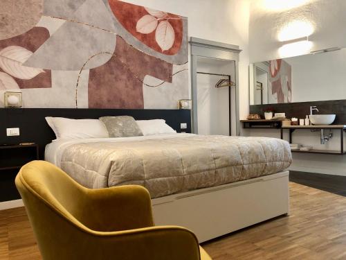 sypialnia z łóżkiem i żółtym krzesłem w obiekcie DIMOR'A' ROOMS w mieście Pitigliano