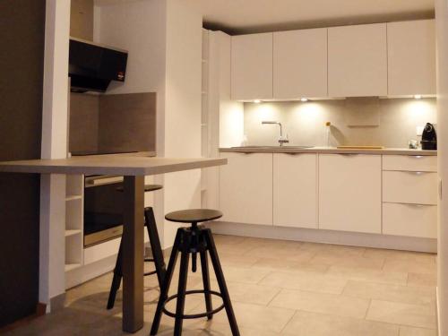 une cuisine avec des placards blancs, un comptoir et un tabouret dans l'établissement Contades Orangerie, à Strasbourg