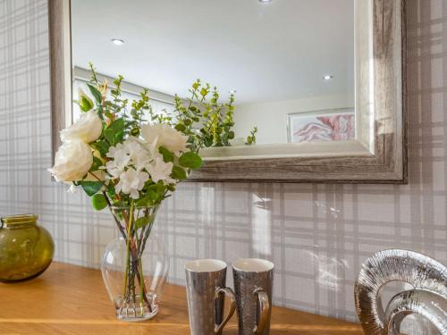 a vase of flowers on a table with a mirror at 2 bed property in Howden 86817 in Scalby