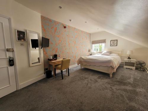 a bedroom with a bed and a desk and a window at Three Tuns Ashwell in Ashwell