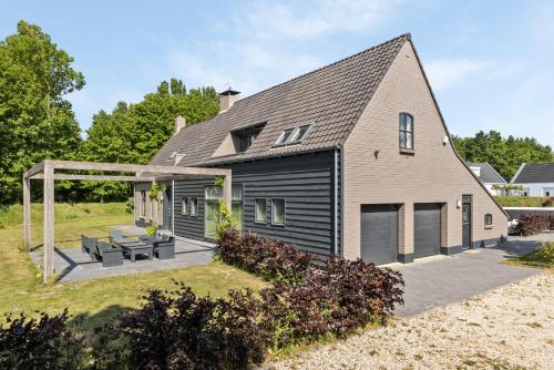 a house with a patio and a roof at Landgoed Hermitage - Villa Euphoria - XXL Zwemspa - Max 10 personen in Ouddorp