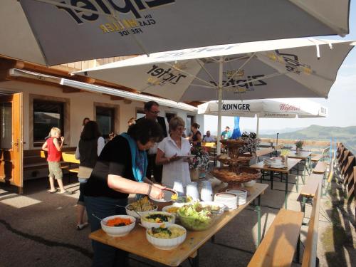 a group of people standing around a table with food at Berggasthof Schatzbergalm in Thierbach