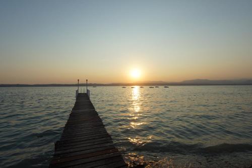 a pier on a lake with the sun setting at Hotel Saviola in Sirmione