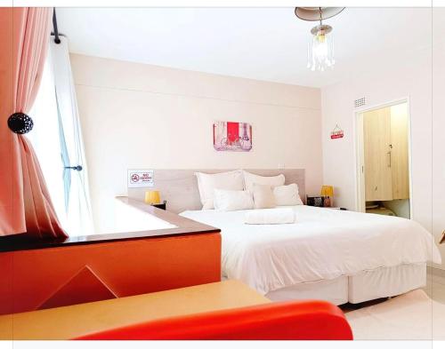 ein Schlafzimmer mit einem großen weißen Bett mit einem Fenster in der Unterkunft New Apartment 3mins walk to shops in Harare