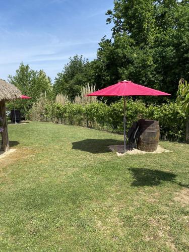 a pink umbrella sitting in the middle of a yard at Le Piquet Résidence-Pavillon in Cazaubon