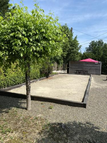 a tree in a yard with a table and a red umbrella at Le Piquet Résidence-Pavillon in Cazaubon
