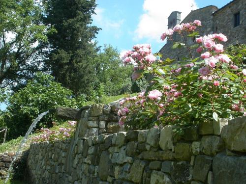 a stone wall with pink flowers and a waterfall at Fattoria Poggerino in Radda in Chianti