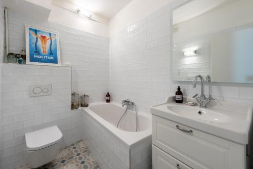 une salle de bain blanche avec une baignoire et un lavabo dans l'établissement Alma - Charmant apt 2 chambres, à Lyon