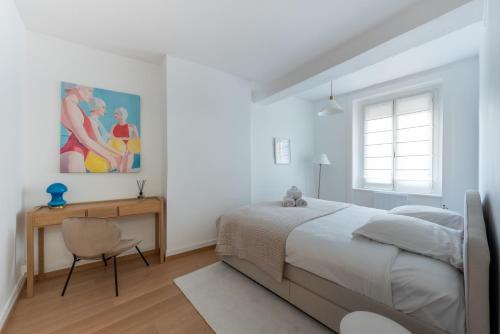 ein weißes Schlafzimmer mit einem Bett und einem Schreibtisch in der Unterkunft Alma - Charmant apt 2 chambres in Lyon