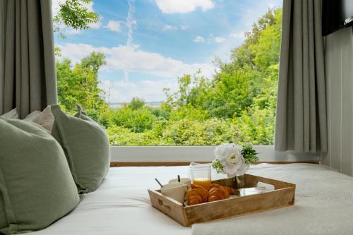 a tray of bread and candles on a bed with a window at Art Studio - Connect to Nature in the Hot Tub at Cosy Studio in Blandford Forum