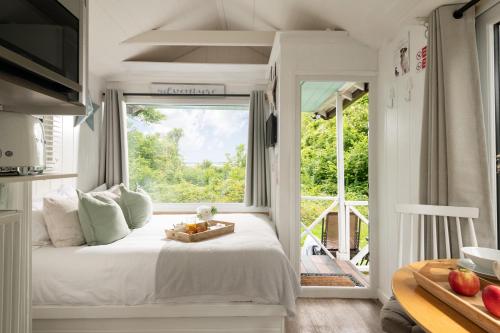a bedroom with a bed and a large window at Art Studio - Connect to Nature in the Hot Tub at Cosy Studio in Blandford Forum