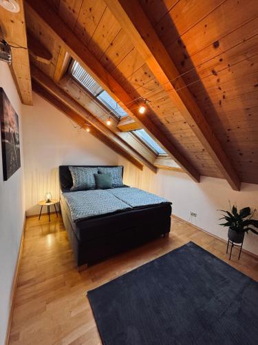 sypialnia z łóżkiem w pokoju z drewnianym sufitem w obiekcie Ferienwohnung Alpenglühen w mieście Sonthofen