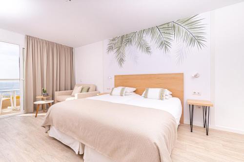 a white bedroom with a large bed and a chair at Atlantic Holiday Hotel in Callao Salvaje