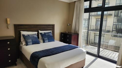 a bedroom with a bed with blue pillows and a window at Accommodation Front - Regal 6 Sleeper Across the Ocean in Durban