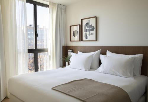 a bedroom with a large white bed with a window at The Onsider - Penthouse 3 Bedroom Apartment - Paseo de Gracia in Barcelona
