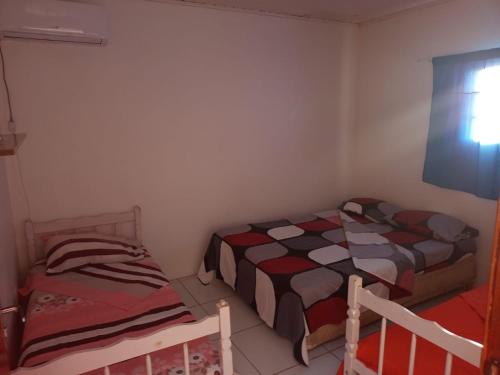 2 camas en una habitación pequeña con ventana en Pousada navarro en São Gabriel