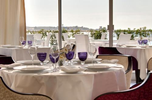a dining room with white tables and purple wine glasses at Grand Hôtel Thalasso & Spa in Saint-Jean-de-Luz