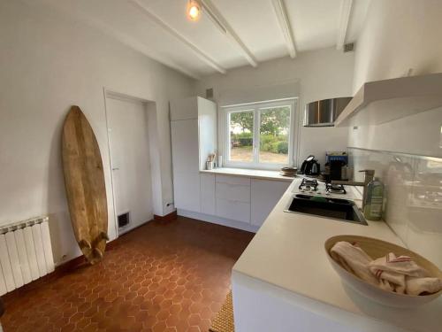 d'une cuisine avec des comptoirs blancs, un évier et une fenêtre. dans l'établissement Maison plage de Pors Péron, à Beuzec-Cap-Sizun