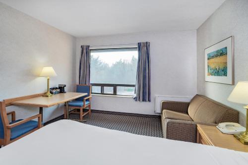 a hotel room with a bed and a desk and a window at Travelodge by Wyndham Bridgewater in Bridgewater