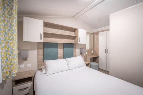 a bedroom with a white bed and white cabinets at Llanrhidian Holiday Park in Llanmorlais