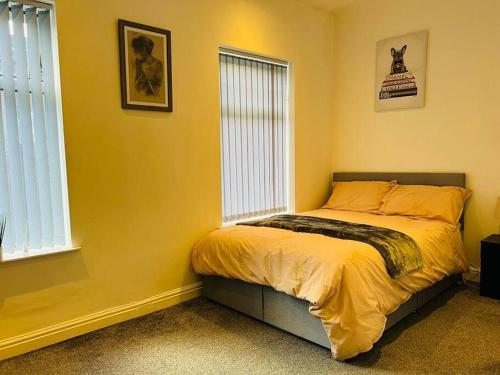 a bedroom with a bed with yellow walls and windows at 4 Bed 4 Bath 6 Guest Lovely home in Stoke on Trent