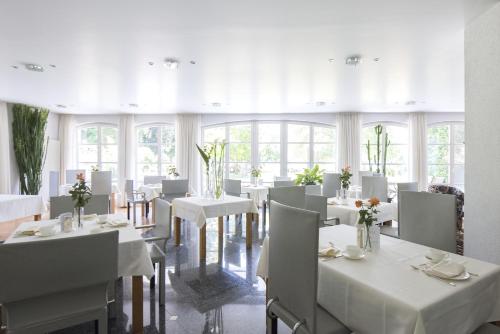 un comedor con mesas blancas y sillas blancas en ArtVilla am See - buchbar April-Mai 2024, en Radolfzell am Bodensee