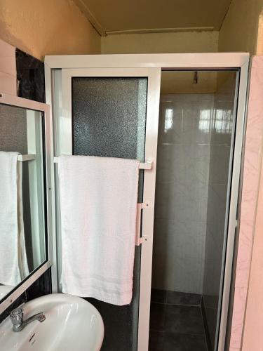 a bathroom with a sink and a shower with a towel at STONE CASTLE HOTEL in Freetown