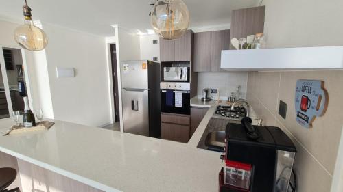 a kitchen with a white counter and a refrigerator at Departamento con espectacular vista al mar Arica, Condominio Ayllu in Arica