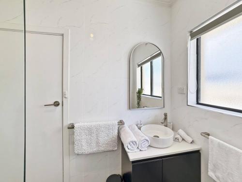 a white bathroom with a sink and a mirror at 'The Grange' Coastal Charm near Henley Beach in Adelaide