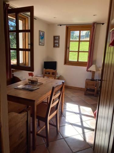 a dining room with a wooden table and two windows at Marie Mont Blanc in Saint-Gervais-les-Bains