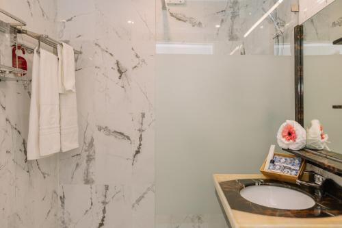 a bathroom with a sink and a marble wall at Monicca Collection Suites and Residences in Albufeira