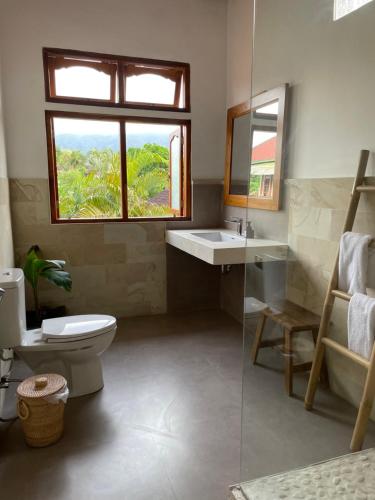 baño con aseo y lavabo y ventana en Kubu Elsa Bali en Lovina