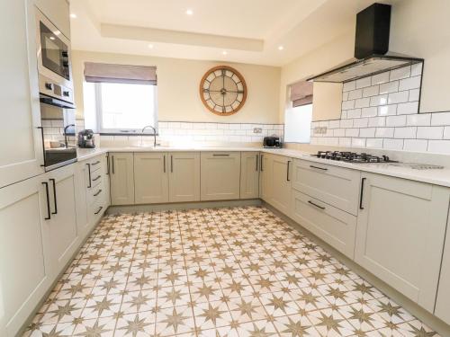 a kitchen with white cabinets and a tile floor at Austwick in Skipton