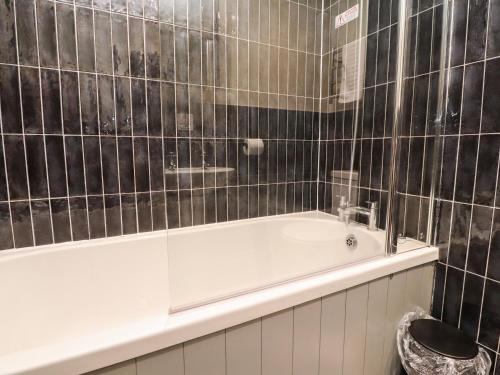 a black tiled bathroom with a white bath tub at Austwick in Skipton