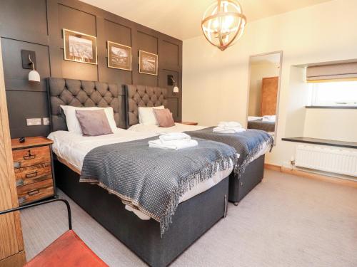 a bedroom with two beds and a mirror at Austwick in Skipton