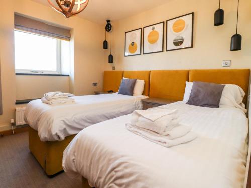 a room with two beds with white sheets at Austwick in Skipton