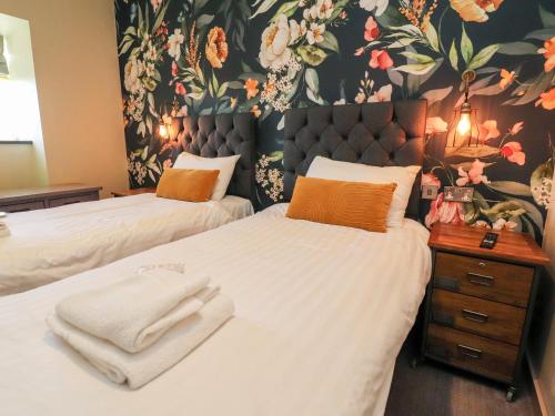 a bedroom with two beds and a floral wallpaper at Rathmell in Skipton