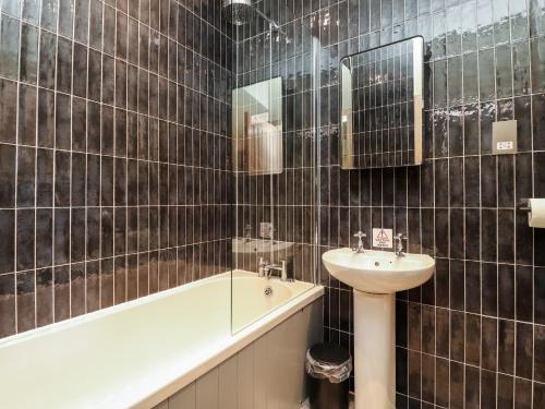 a black tiled bathroom with a sink and a bath tub at Rathmell in Skipton