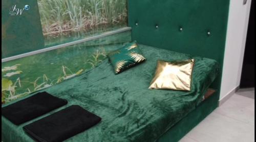 a green bed with two gold pillows on it at KochloChill in Ruda Śląska