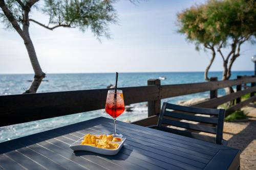 a drink sitting on a table next to the beach at Villaggio Torre Ruffa in Capo Vaticano