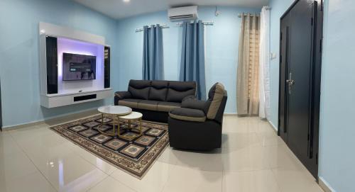 ein Wohnzimmer mit einem Sofa und einem TV in der Unterkunft Homestay ShimahJay Umbai Melaka in Malakka