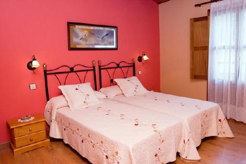 een slaapkamer met 2 bedden en een rode muur bij La Artesana in Posada de Rengos
