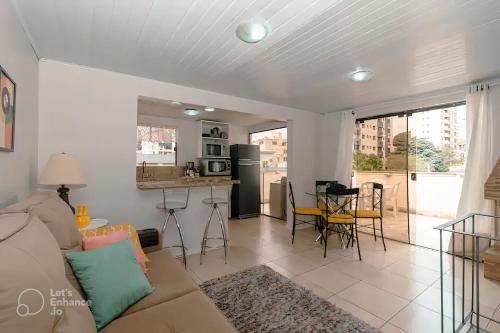 a living room with a couch and a kitchen at Aps de frente com sacada ou terraço a 10 minutos do Aeroporto in Porto Alegre