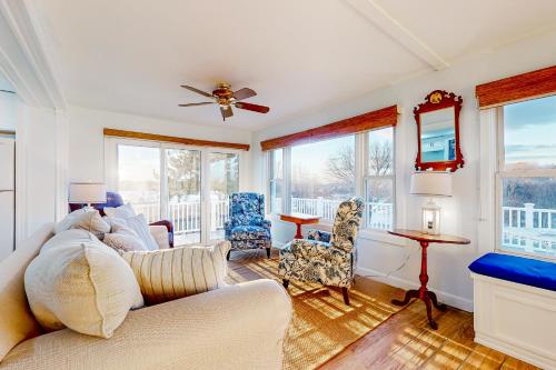 a living room with a couch and chairs and windows at Goat Hill Cottage in Beverly