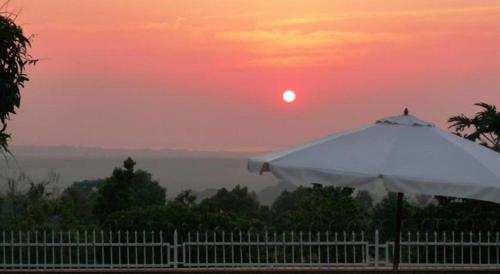 a white umbrella with a sunset in the background at Carpe Diem Guesthouse in Entebbe